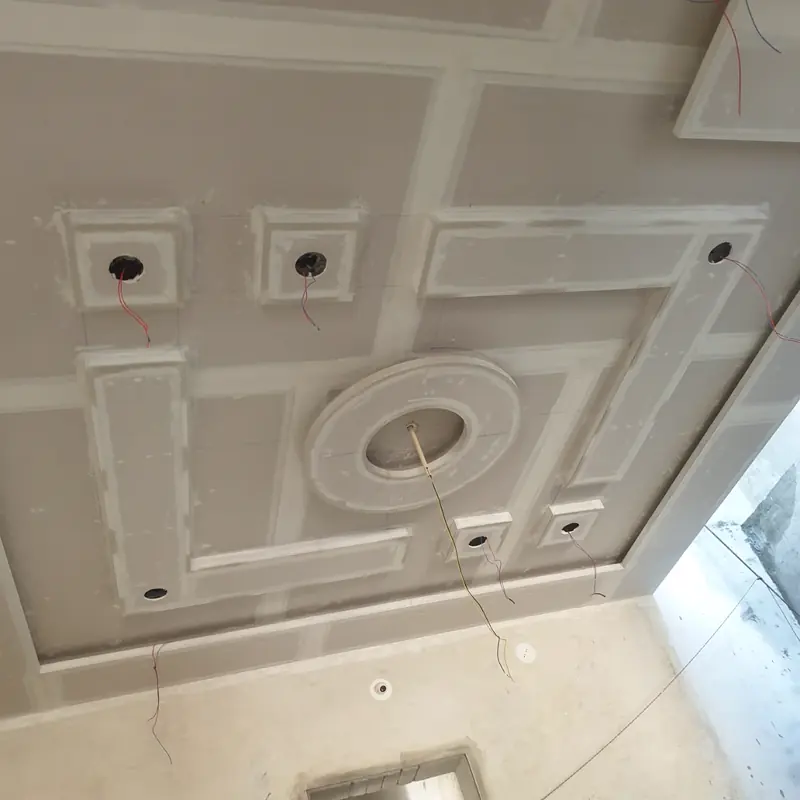 Gypsum false ceiling under construction, showing coffered framing, a central ceiling rose and wiring left for light points