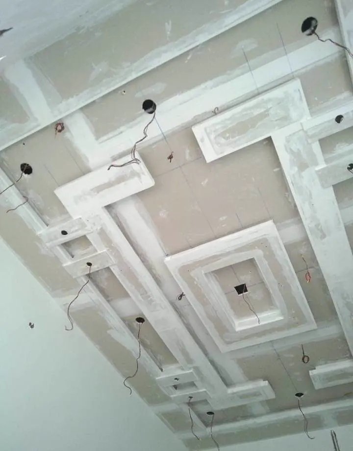 Layered POP false ceiling mid-construction with stepped rectangular recesses and hanging wiring